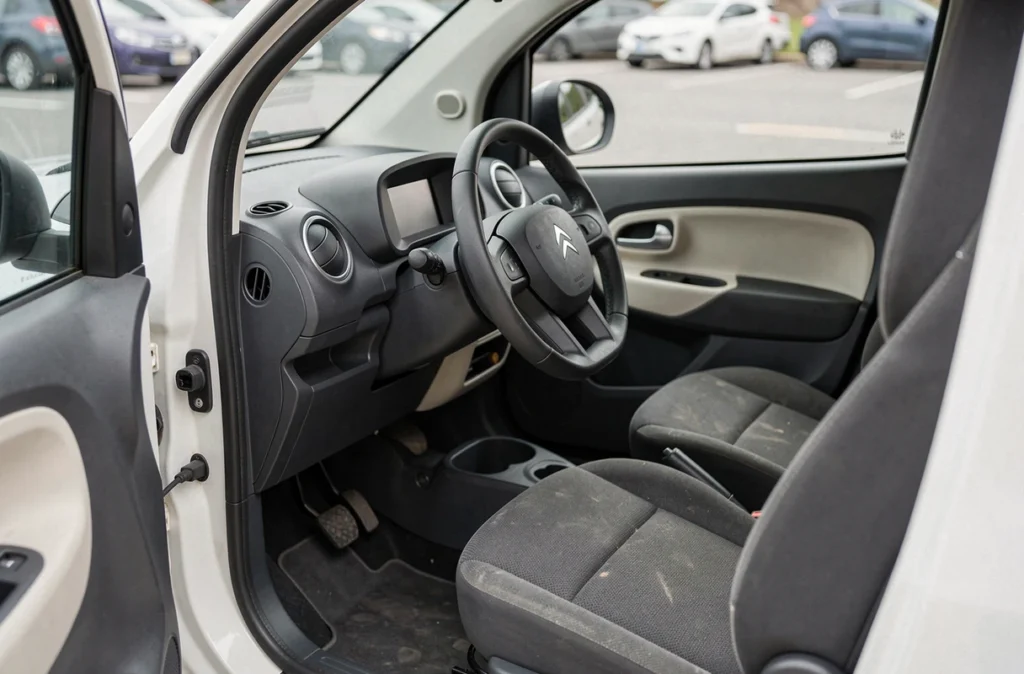 Intérieur d'une Citroën Ami d'occasion avec tableau de bord minimaliste et siège textile usé