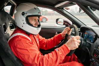 Pilote en combinaison rouge au volant d'une voiture de circuit lors d'un stage de pilotage